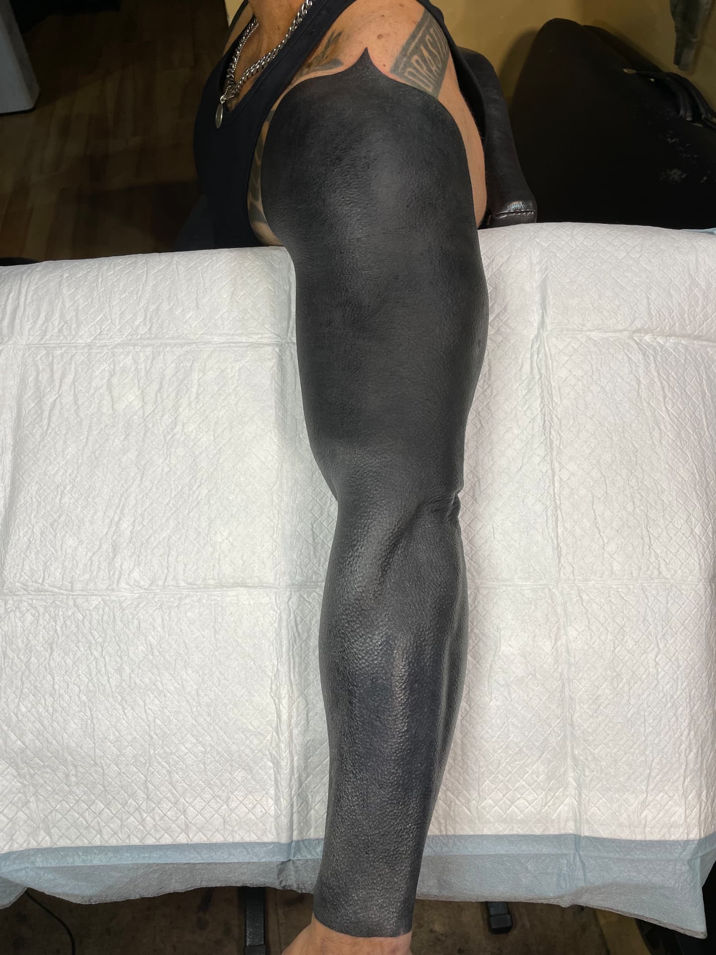 Full arm blackout tattoo extending from the shoulder to the wrist.