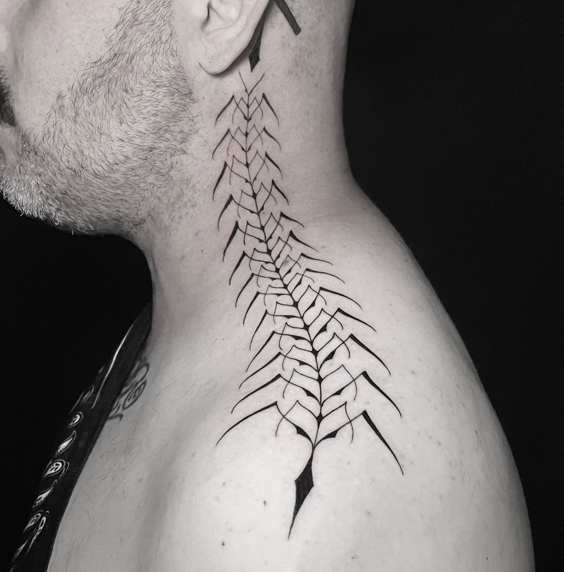 Fine black centipede tattoo extending down the side of the neck toward the shoulder.