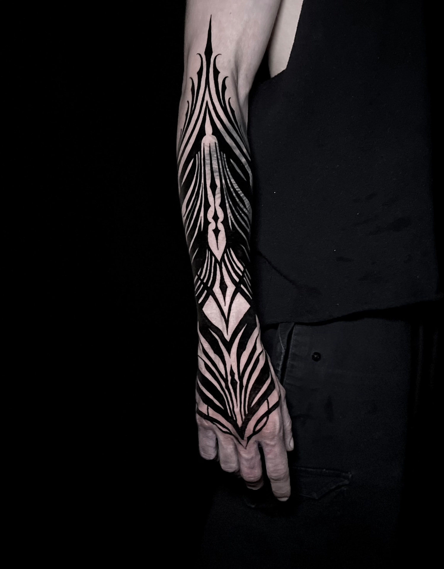 High-contrast ornamental blackwork tattoo extending down the forearm and onto the hand.