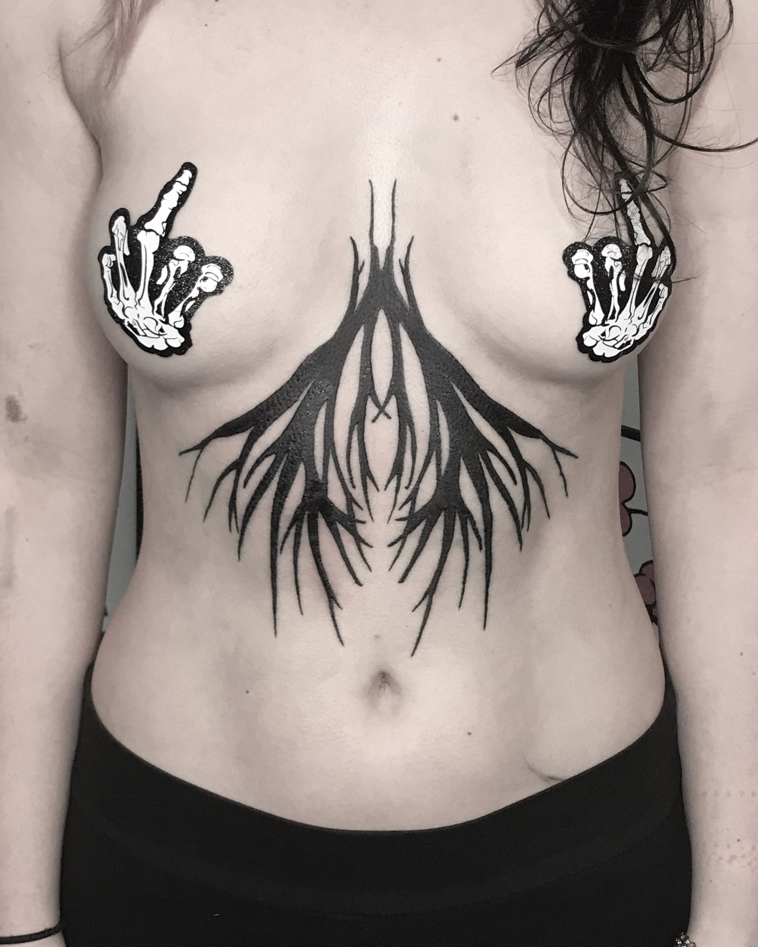 Blackwork flame-shaped ornamental tattoo centred on the sternum.