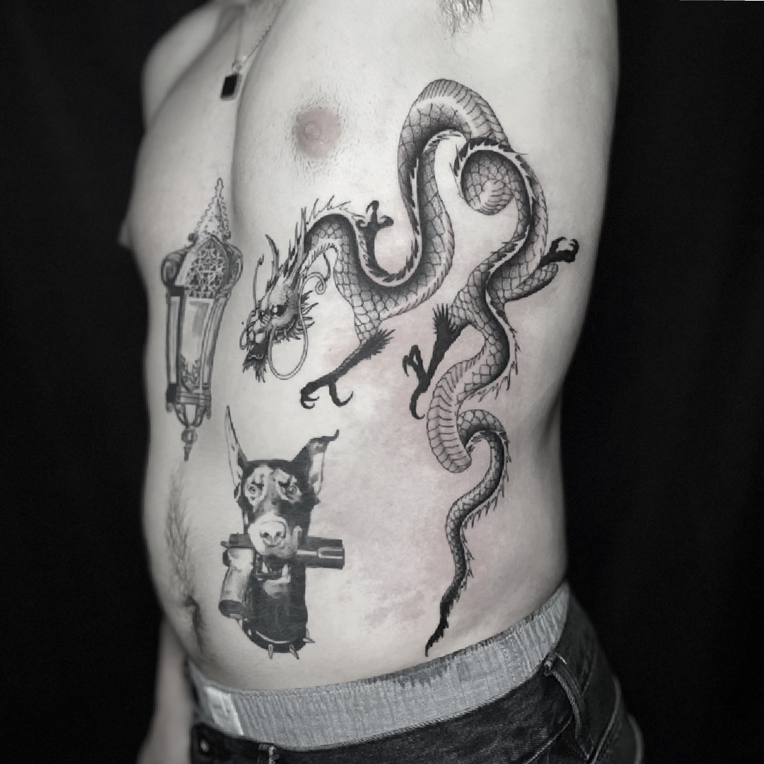 Black and grey dragon tattoo with a lantern and dog's head on the ribs.