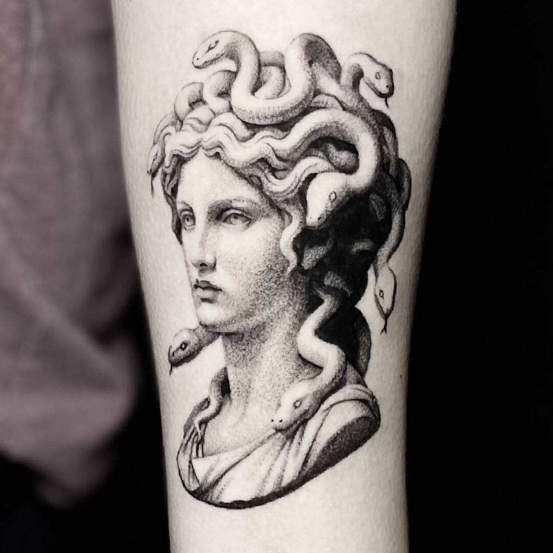 Black and grey realism tattoo of a classical Medusa bust with serpents, on the lower leg.