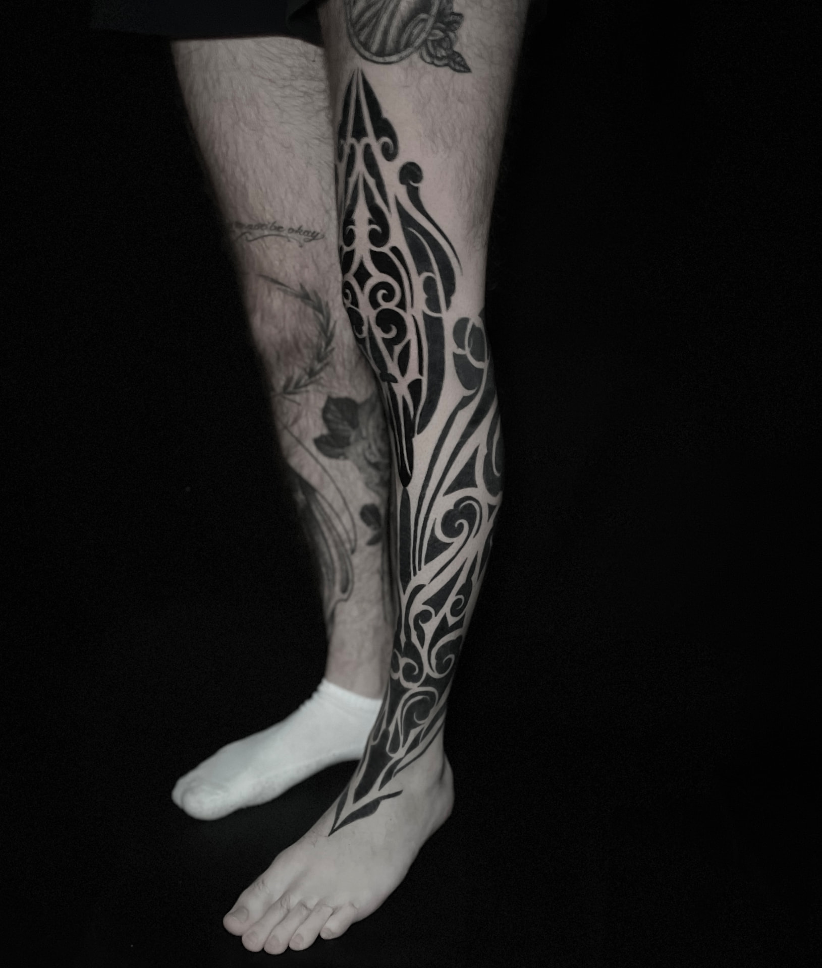 Bold ornamental blackwork tattoo flowing down the shin to the ankle.
