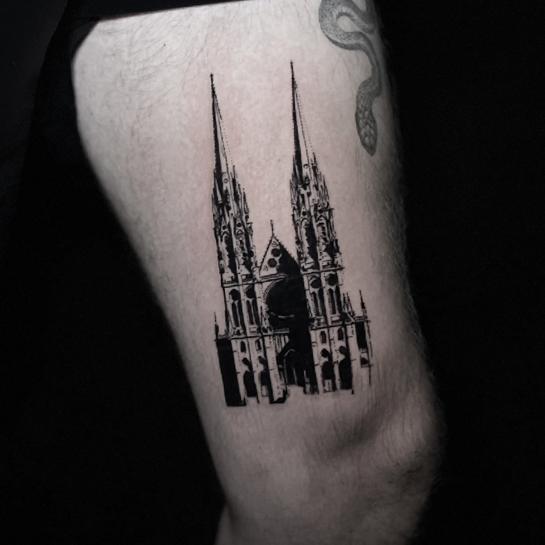 Black and grey gothic cathedral tattoo on the upper arm.
