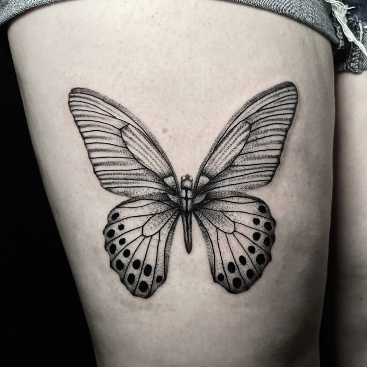 Fineline butterfly tattoo with delicate stipple shading on the thigh.